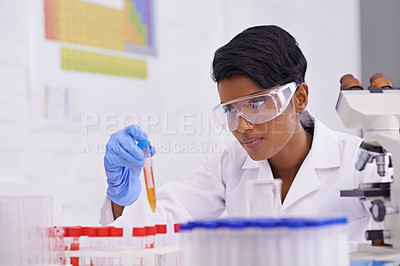 Buy stock photo A beautiful young scientist dropping a substance into test tubes in her lab