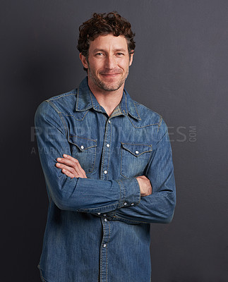 Buy stock photo Studio portrait of a handsome man standing with his arms folded on a gray background