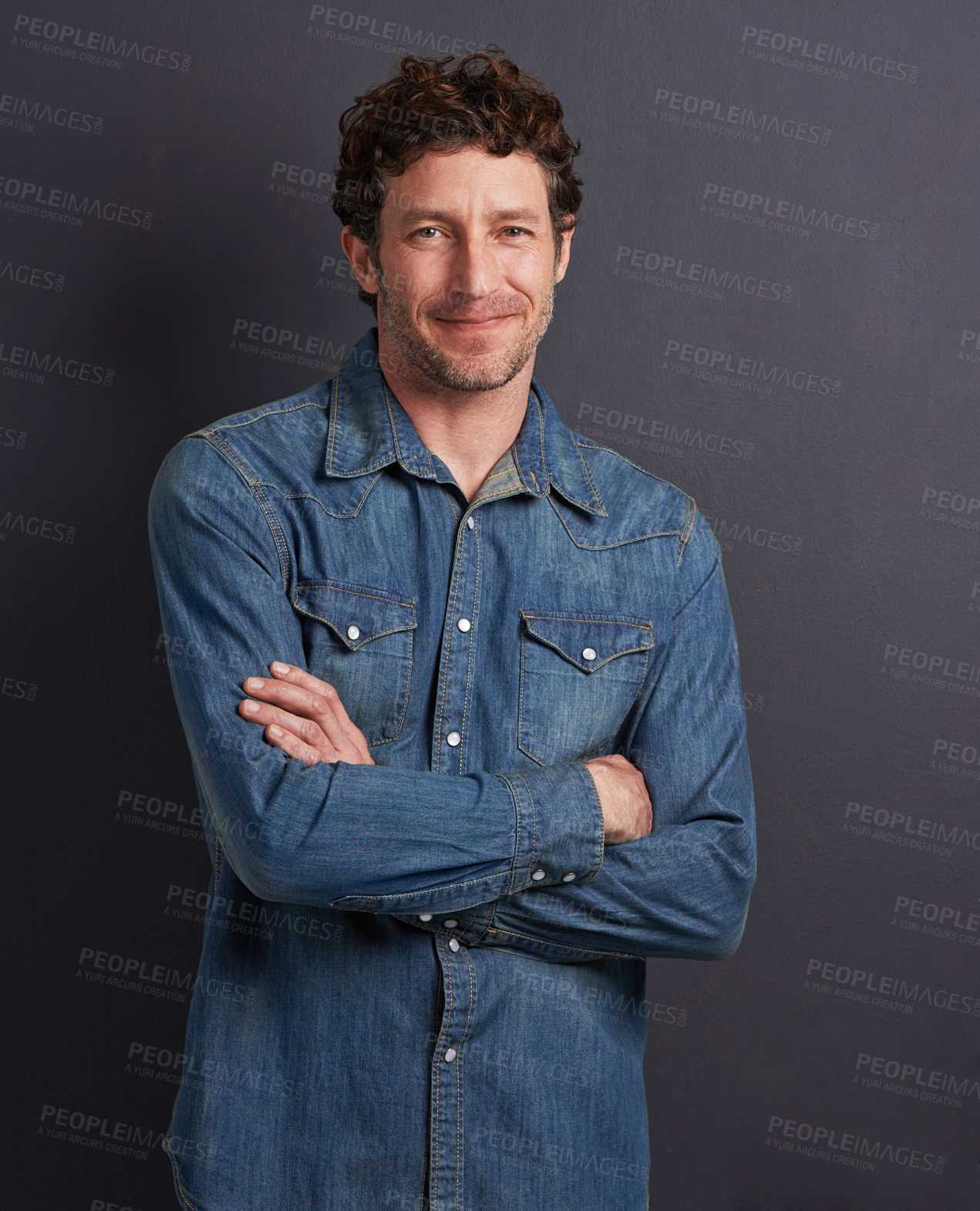 Buy stock photo Studio portrait of a handsome man standing with his arms folded on a gray background