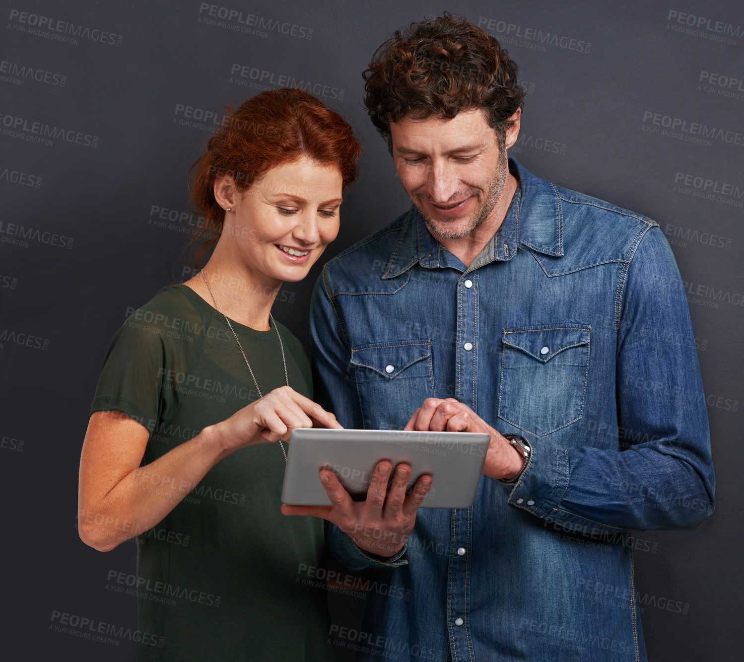 Buy stock photo Happy couple, typing and communication with tablet for research or networking on a dark studio background. Young man and woman with smile on technology for online search, browsing or scrolling on app