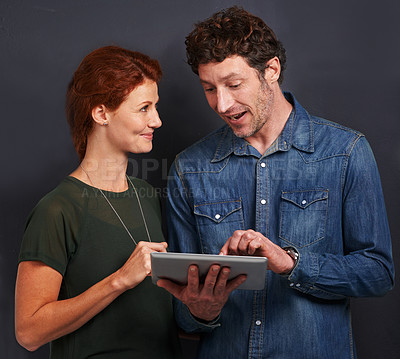 Buy stock photo Tablet, man and woman in studio together with casual style, connection and networking for creative professional. Internet, communication and team with digital app for online search on dark background