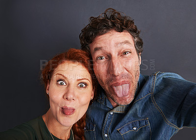 Buy stock photo Portrait of a happy young couple pulling silly faces for a selfie