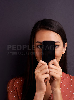 Buy stock photo Portrait, phone screen and woman hiding on mockup space in studio isolated on a gray background. Face, display and person cover with smartphone for advertising, marketing or promo on social media app