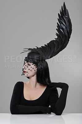 Buy stock photo Fashion, woman and hat with feather in studio for glamour, style and thinking with mystery. Female person, confidence and cap with wing for elegance, luxury and designer clothes on gray background