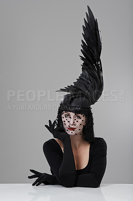 Buy stock photo Shot of a young woman in a wing-shaped headpiece sitting in a studio