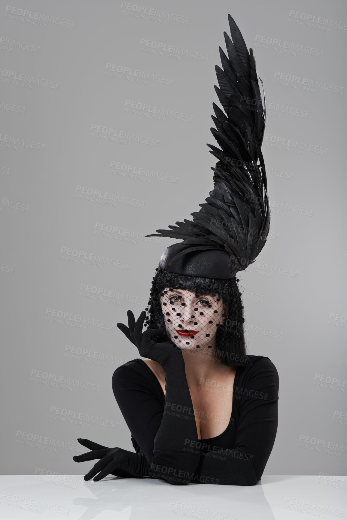 Buy stock photo Shot of a young woman in a wing-shaped headpiece sitting in a studio