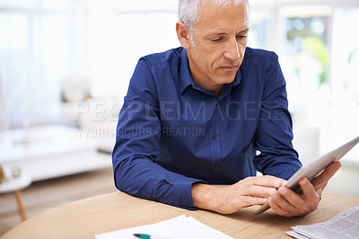 Buy stock photo Shot of a mature man using a digital tablet at home