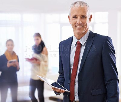 Buy stock photo Shot of a mature businessman standing in the foreground with two colleagues behind him