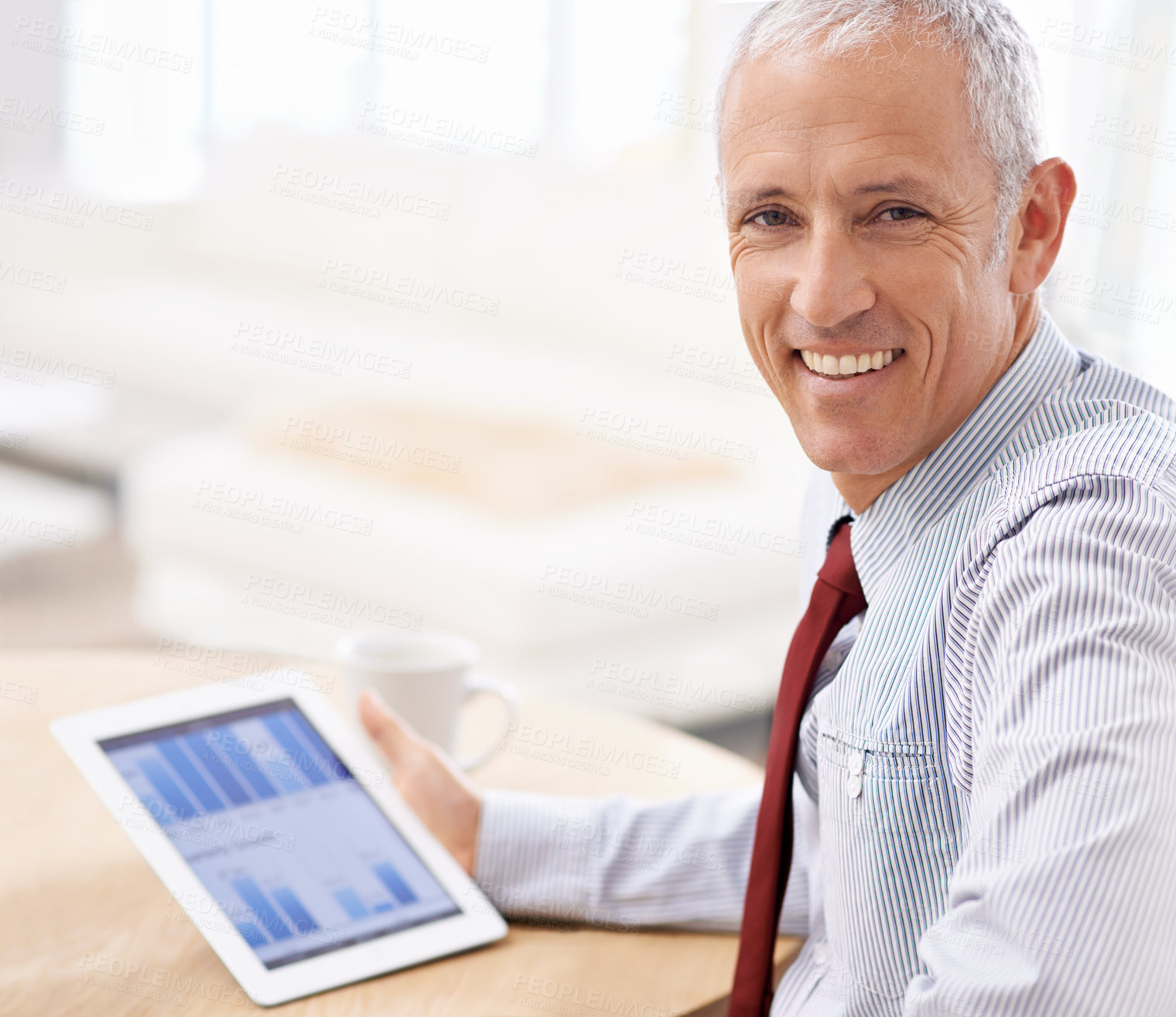 Buy stock photo Shot of a businessman looking pleased at the quarterly results he sees on his tablet