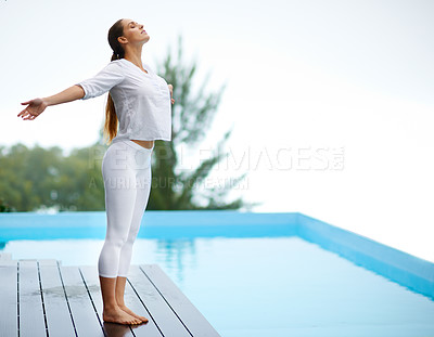 Buy stock photo Shot of a gorgeous young woman doing yoga outdoors beside a pool