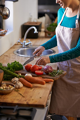 Buy stock photo Cropped shot of an attractive young woman chopping vegetables in the kitchen