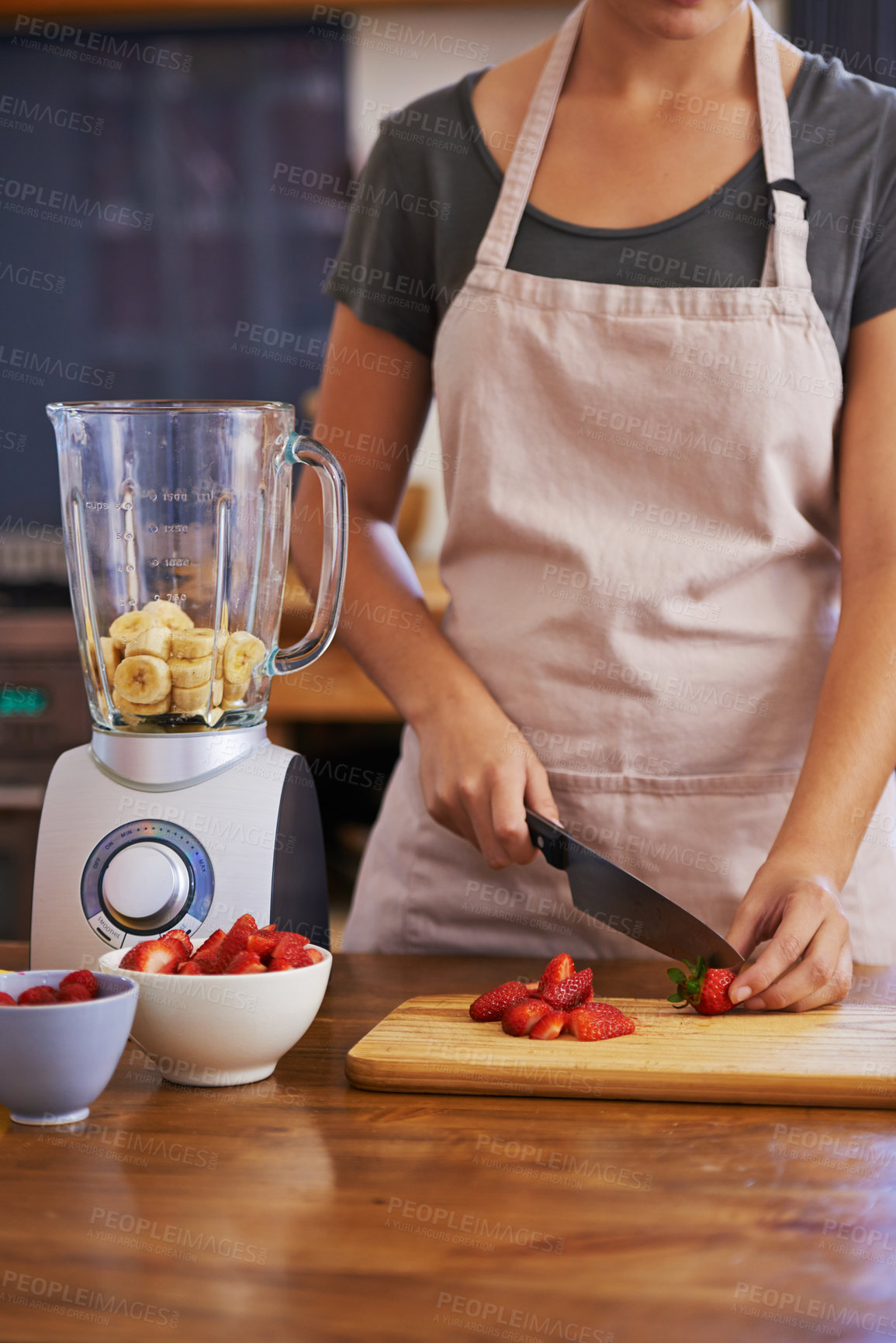 Buy stock photo Cropped shot of an attractive young woman chopping fruit to make a smoothie