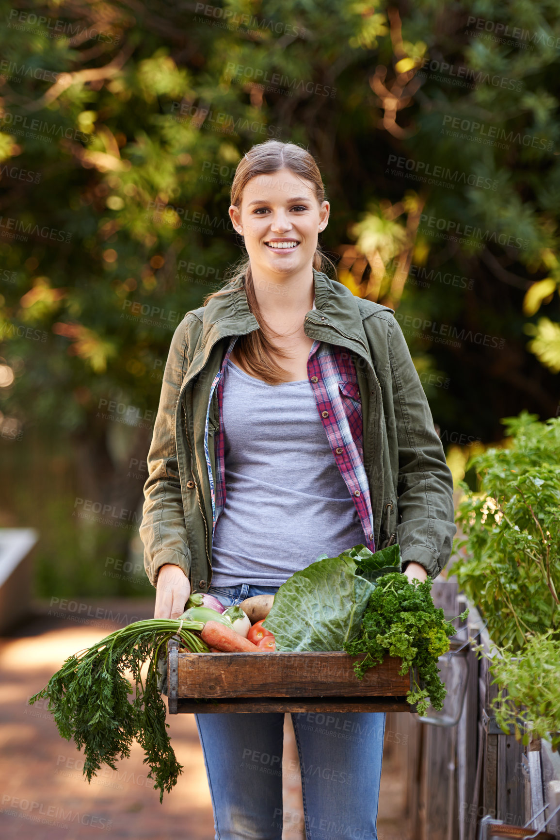 Buy stock photo Portrait of a happy young woman holding a crate full of freshly picked vegetables