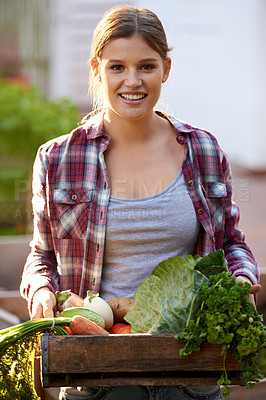Buy stock photo Portrait of a happy young woman holding a crate full of freshly picked vegetables
