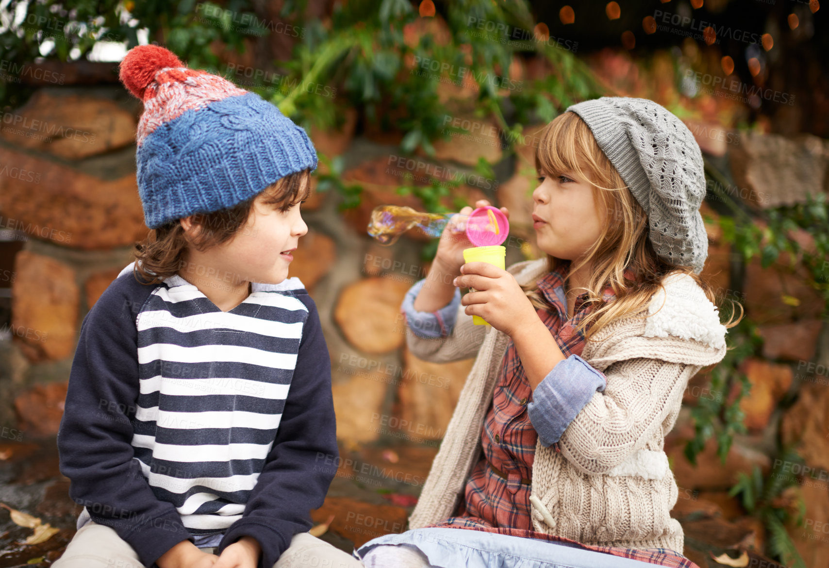 Buy stock photo Shot of two cute children blowing bubbles together outdoors