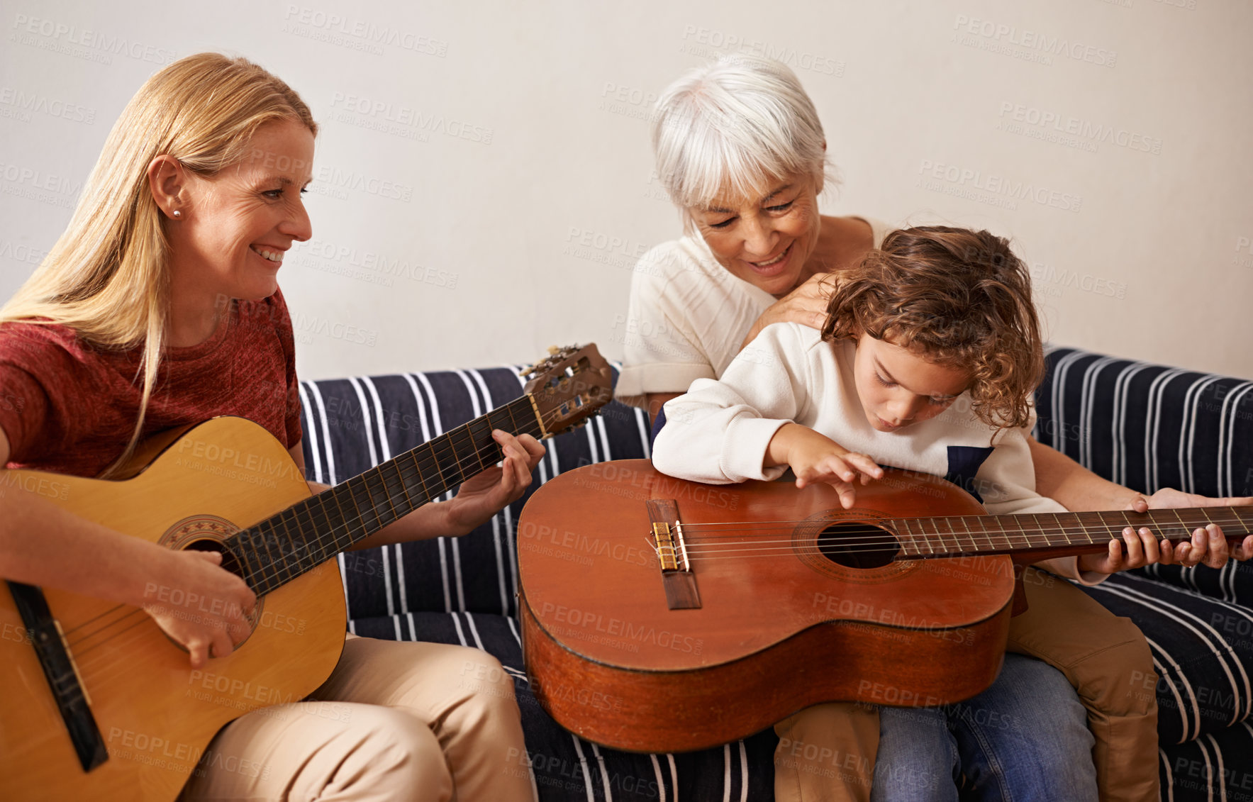 Buy stock photo Shot of a little boy and his mother playing guitar with his grandmother sitting by