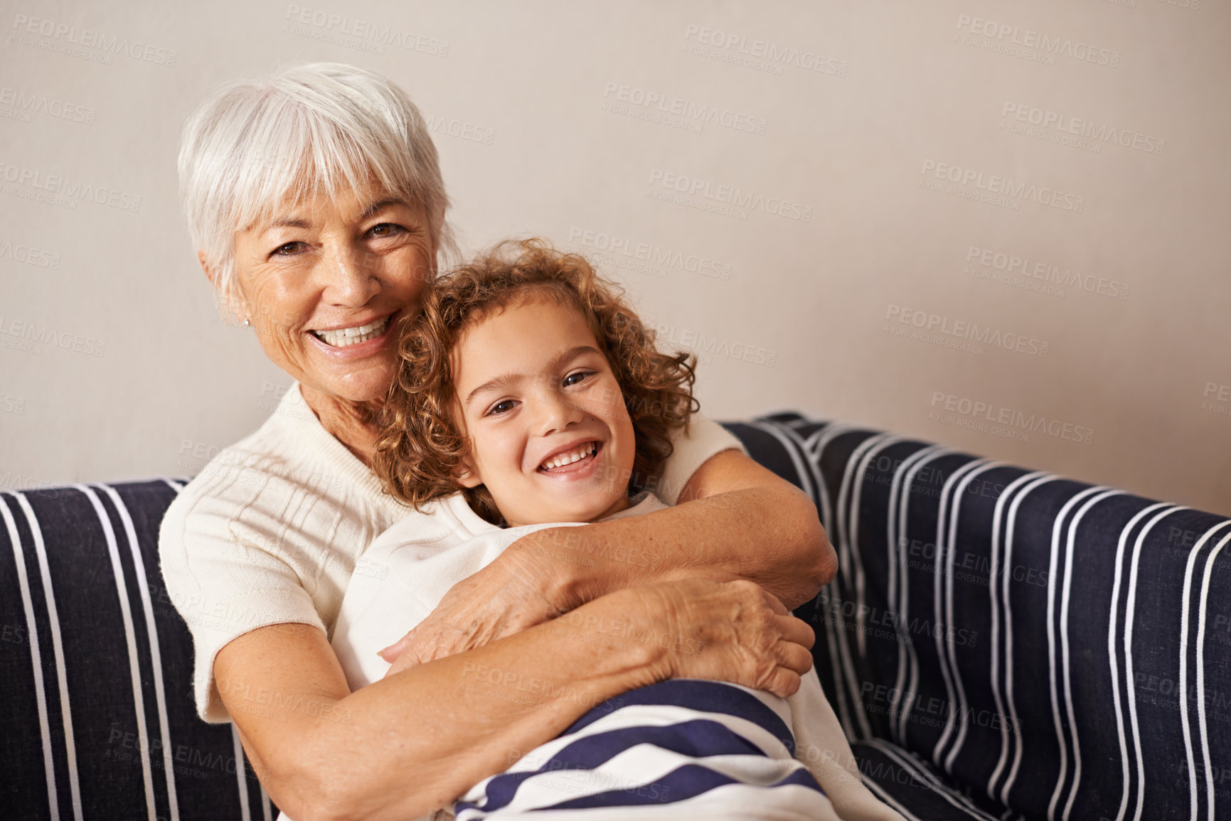 Buy stock photo Shot of a grandmother embracing her grandson while they sit on the sofa