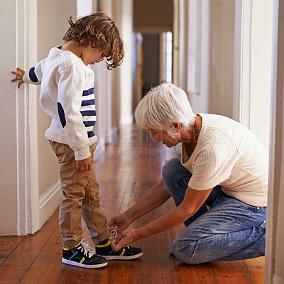 Buy stock photo Grandmother, child and happy helping elderly person, kid with shoelace and children development with grandchild. Together, family home and support for bonding, care and tech for learning with woman