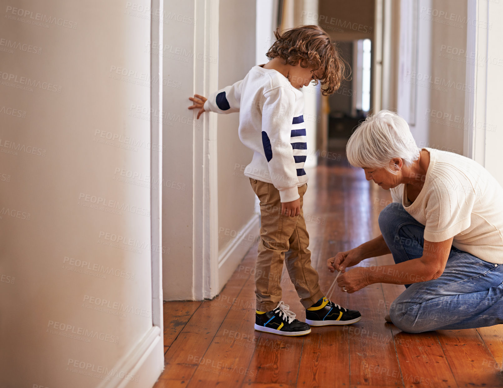 Buy stock photo Shot of a grandmother tying her grandson's shoelaces for him