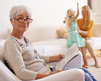 Buy stock photo Portrait of a senior woman sitting and reading with her family in the background