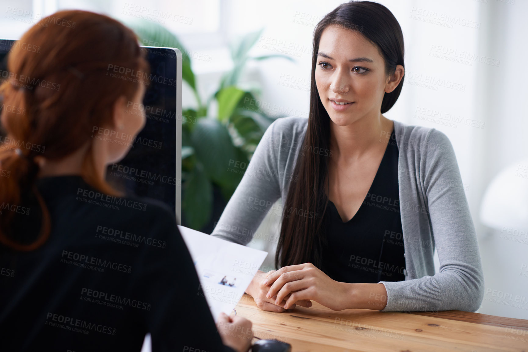 Buy stock photo Shot of two young professionals having a discussion at a desk
