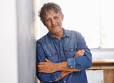 Buy stock photo Portrait of a mature businessman standing with his arms folded in an office setting