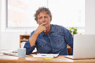 Buy stock photo Shot of a mature businessman sitting at his office desk and looking thoughtful