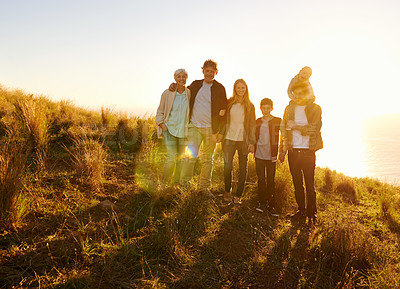 Buy stock photo A portrait of a happy family standing on a grassy hill at sunset