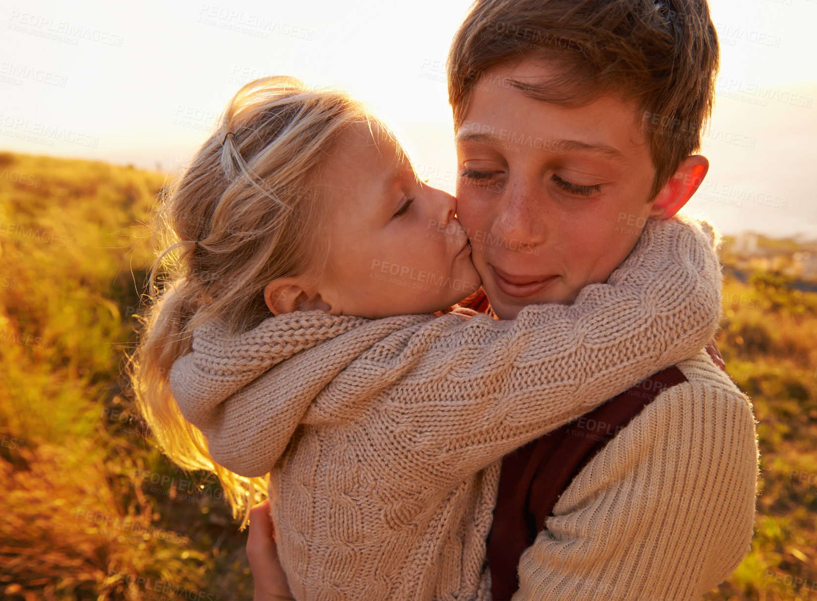 Buy stock photo Cropped shot of a little girl giving her brother a kiss on the cheek while outdoors