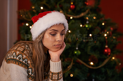 Buy stock photo Cropped shot of a beautiful young woman sitting beside a Christmas tree