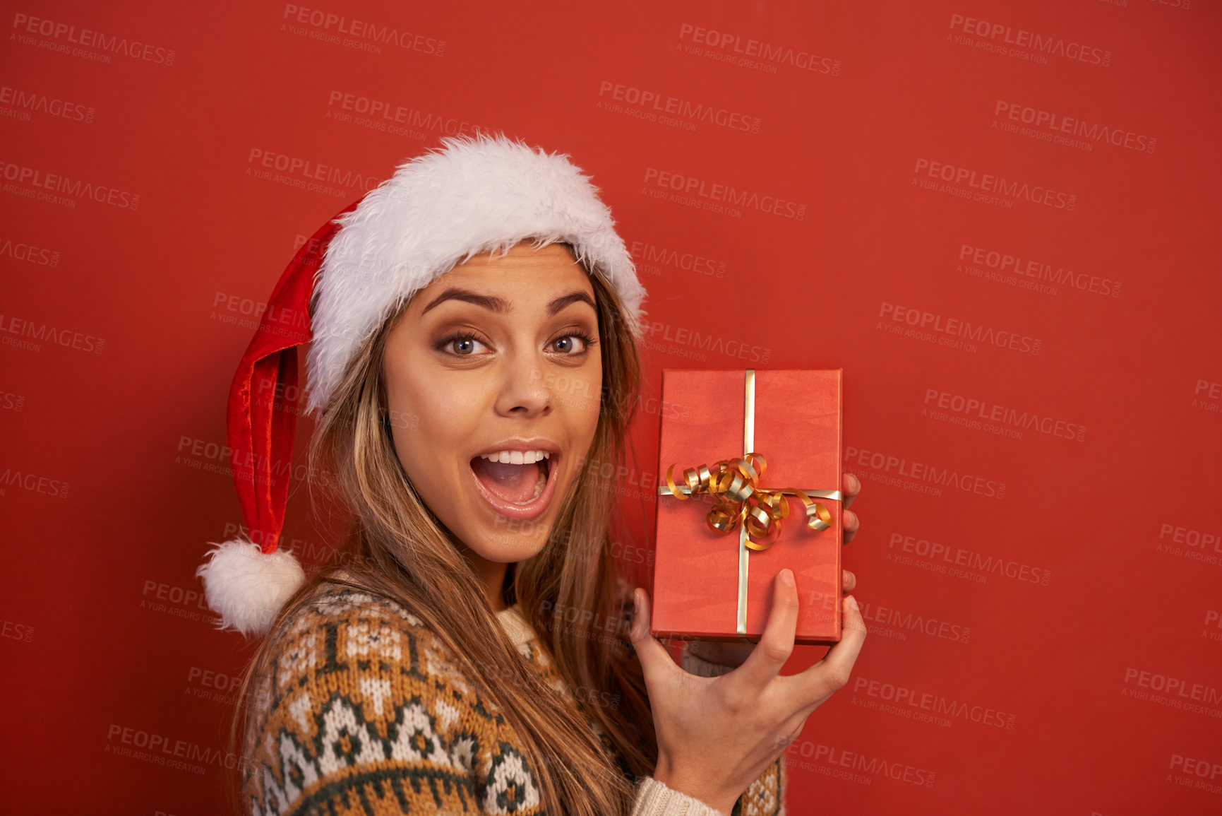 Buy stock photo Happy woman, portrait and Christmas with gift for festive season or December holiday on a red studio background. Face of female person, surprise or wow with hat for special present on mockup space