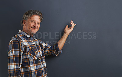 Buy stock photo A portrait of a happy mature man pointing to the space behind him