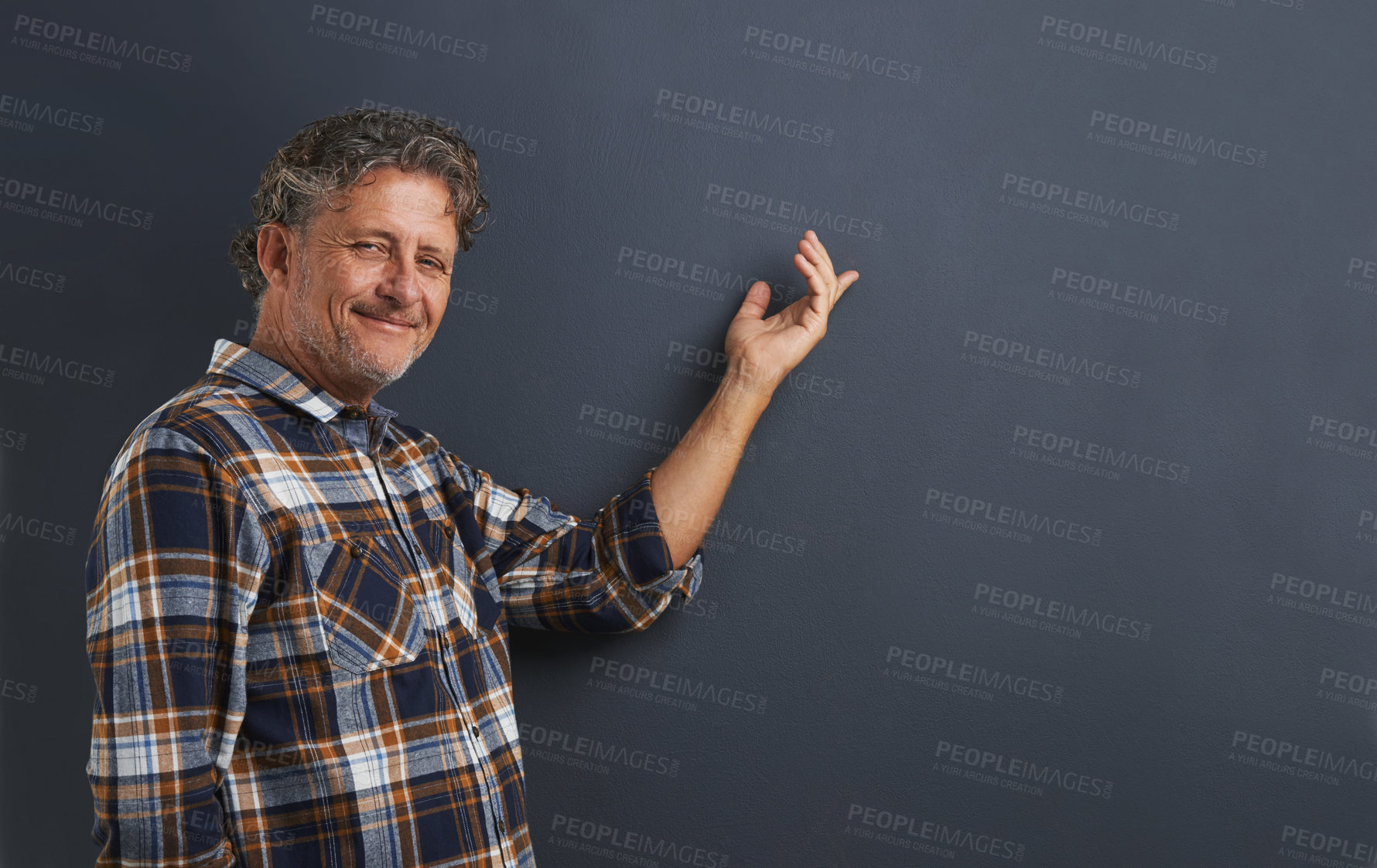Buy stock photo A portrait of a happy mature man pointing to the space behind him