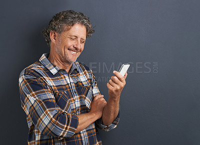 Buy stock photo A cropped shot of a happy mature man using his smartphone