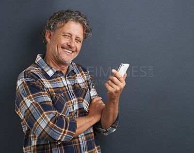 Buy stock photo Mature, man and portrait with cellphone in studio for texting communication, grey background or connectivity. Male person, face and smile with smartphone for online internet, research or mockup space