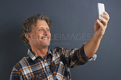 Buy stock photo Mature, man and happy selfie in studio and learning about photography on dark background. Filming, video or click record for profile picture and post online to social media with website or blog