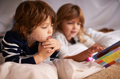 Buy stock photo Reading, blanket fort and kids with book for knowledge, learning and education with flashlight. Bonding, relaxing and young children enjoying story or novel together in tent for sleepover at home.
