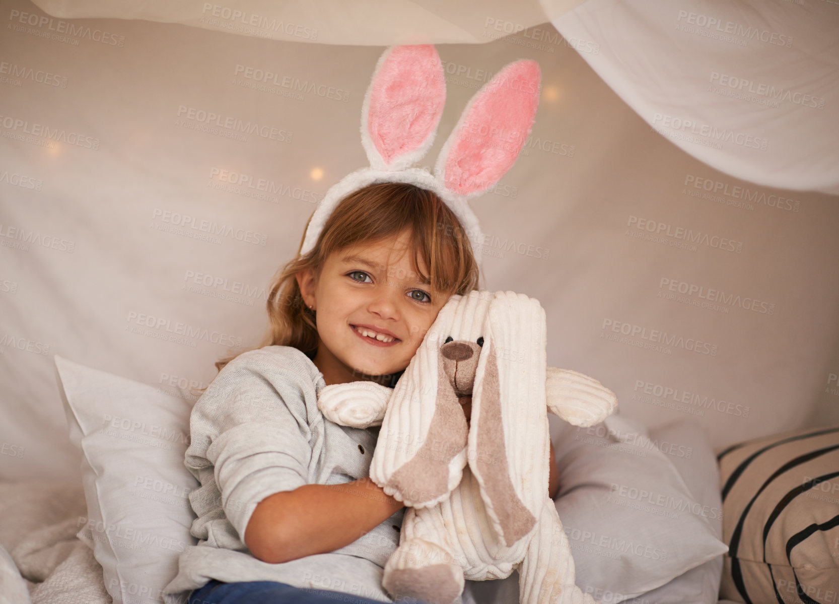 Buy stock photo Girl, kid and bunny ears with teddy bear, soft toys and playing in fort for camping and fun at family home. Happiness, innocent and child with stuffed animal, games for Easter and fun in childhood