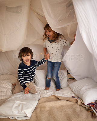 Buy stock photo Shot of two adorable siblings jumping on the mattress underneath their fort