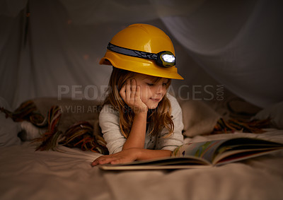 Buy stock photo Shot of an adorable little girl using a headlight to read her book in a fort