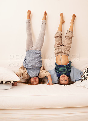 Buy stock photo Portrait of two young children standing on their heads on a sofa