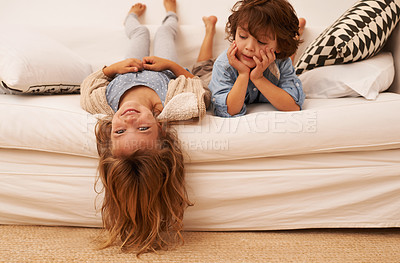 Buy stock photo Shot of two young children lying on a sofa indoors