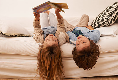 Buy stock photo Shot of two young children lying on their backs and reading a book together