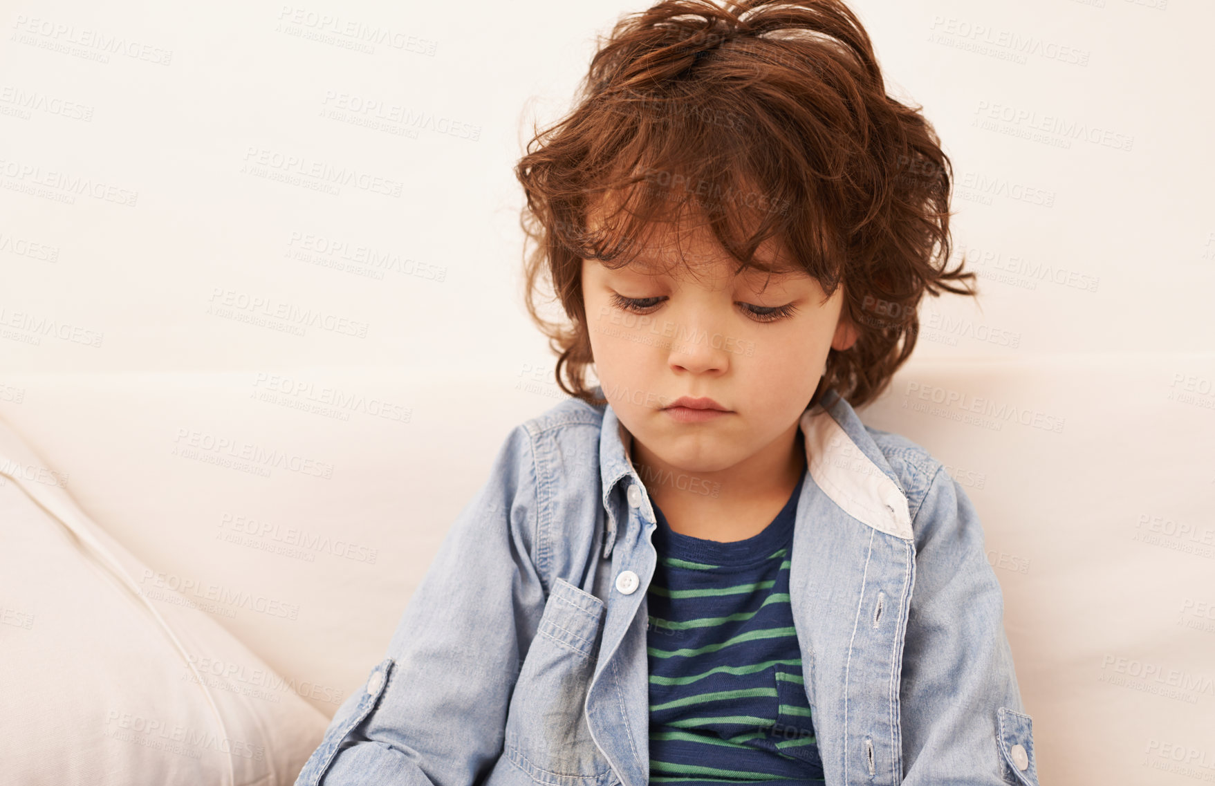 Buy stock photo Shot of an unhappy-looking little boy sitting indoors