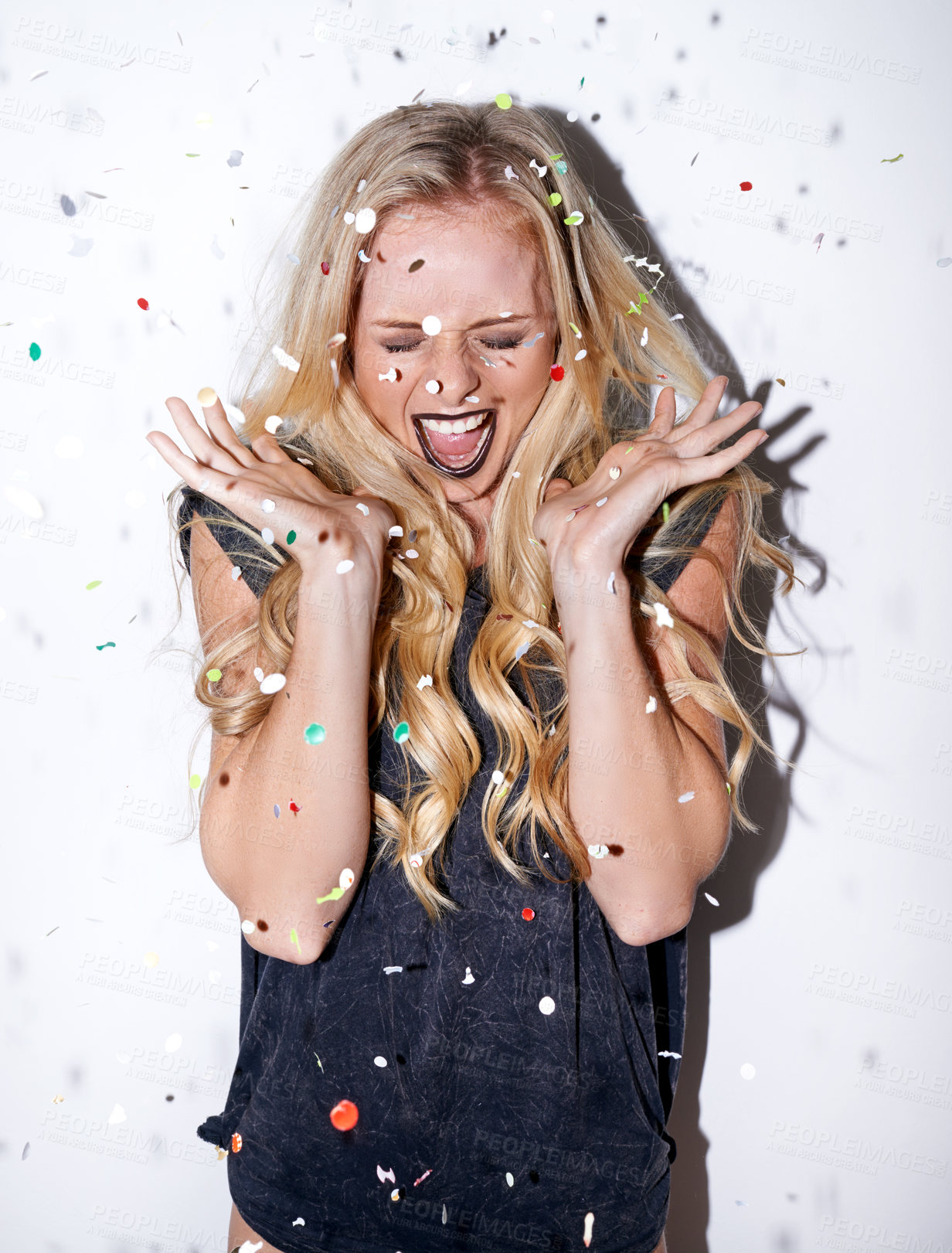 Buy stock photo Shot of an attractive young woman shouting in excitement as confetti falls down on her
