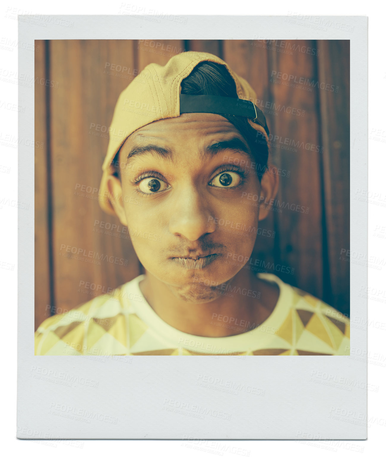 Buy stock photo Portrait, funny face and teenager in home with picture at apartment with wood background in India. Cap, goofy and silly young boy with a hat in house with comic facial expression for photo on mockup