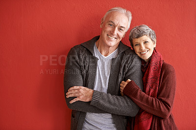 Buy stock photo Shot of an affectionate senior couple standing in front of a red background