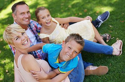 Buy stock photo A portrait of a happy family sitting on the grass together on a sunny day