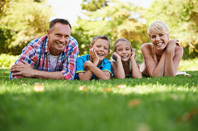 Buy stock photo A front view portrait of a happy family lying on the grass outdoors