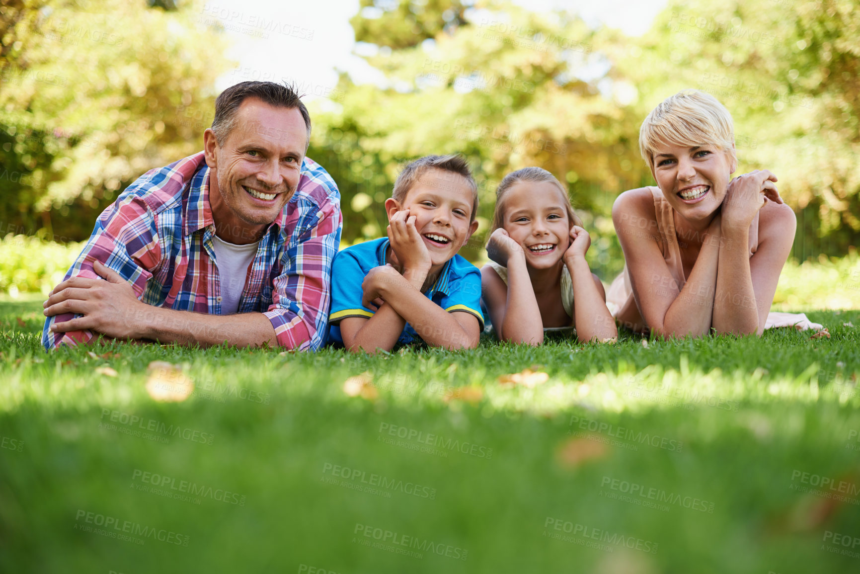 Buy stock photo A front view portrait of a happy family lying on the grass outdoors